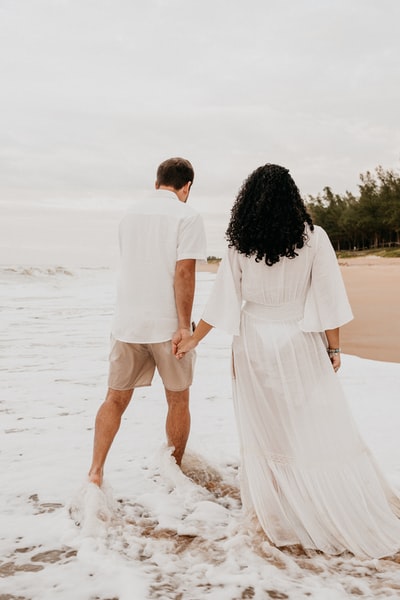 A man and a woman walking on the beach during the day
